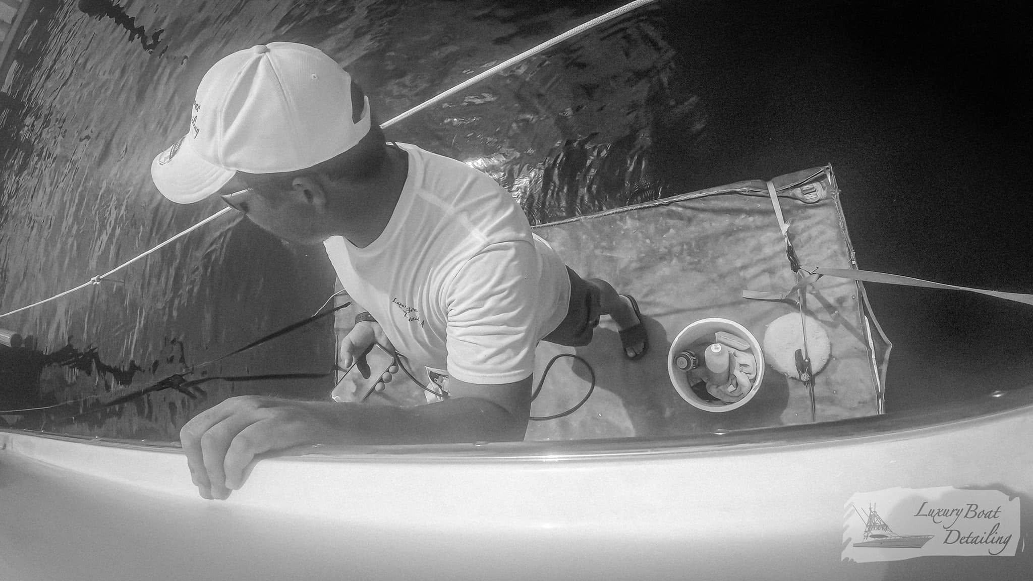Technician working from suspended access to detail a vessel's topsides