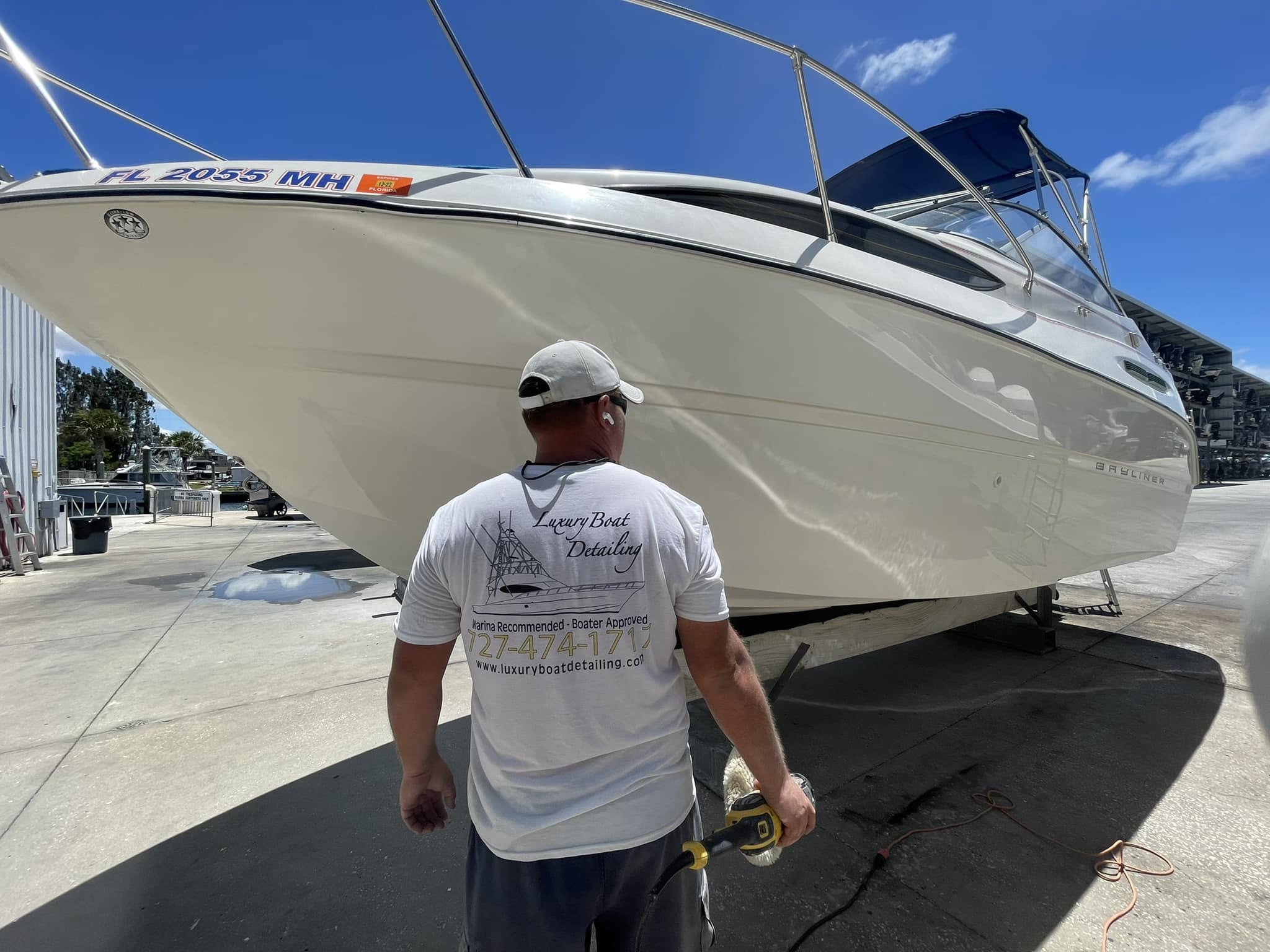 Luxury Boat Detailing technician in a branded shirt detailing the side of a vessel